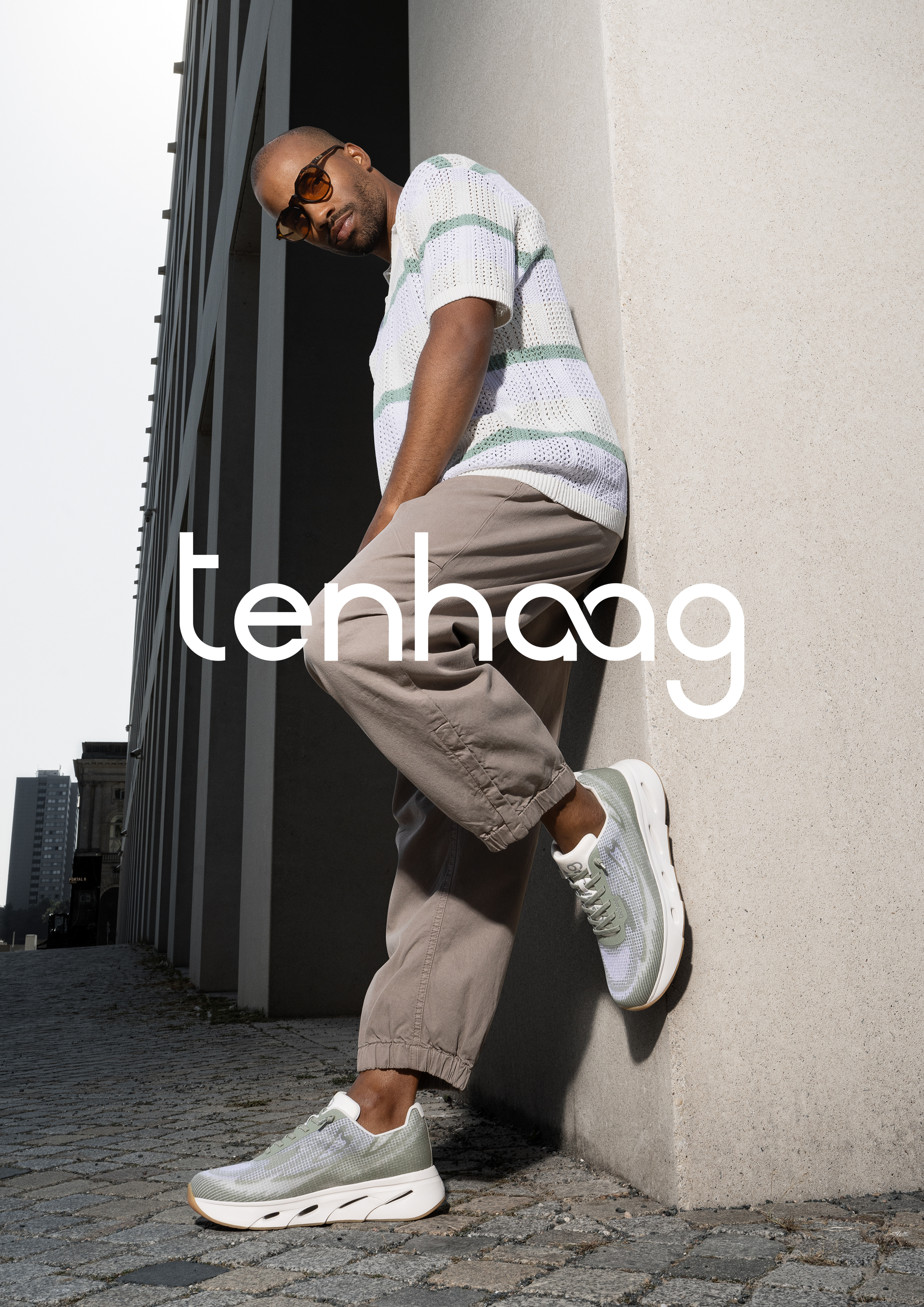 Mann lehnt mit tenhaag sneakern an gebäudewand