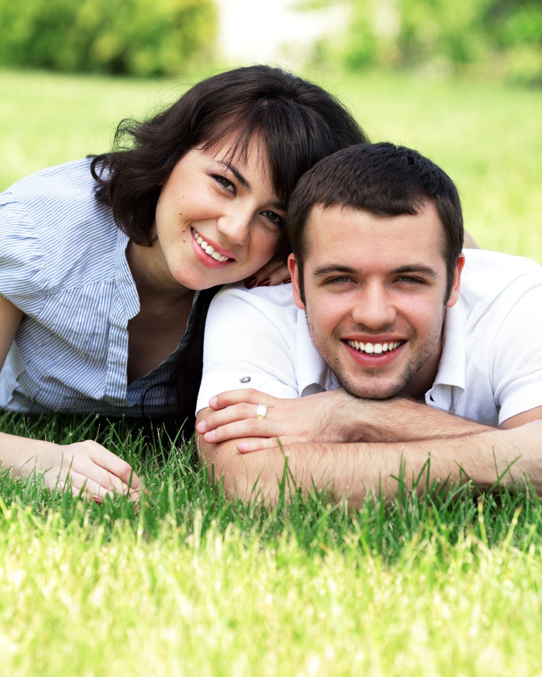 Paar liegt auf Wiese und lächelt in die kamera