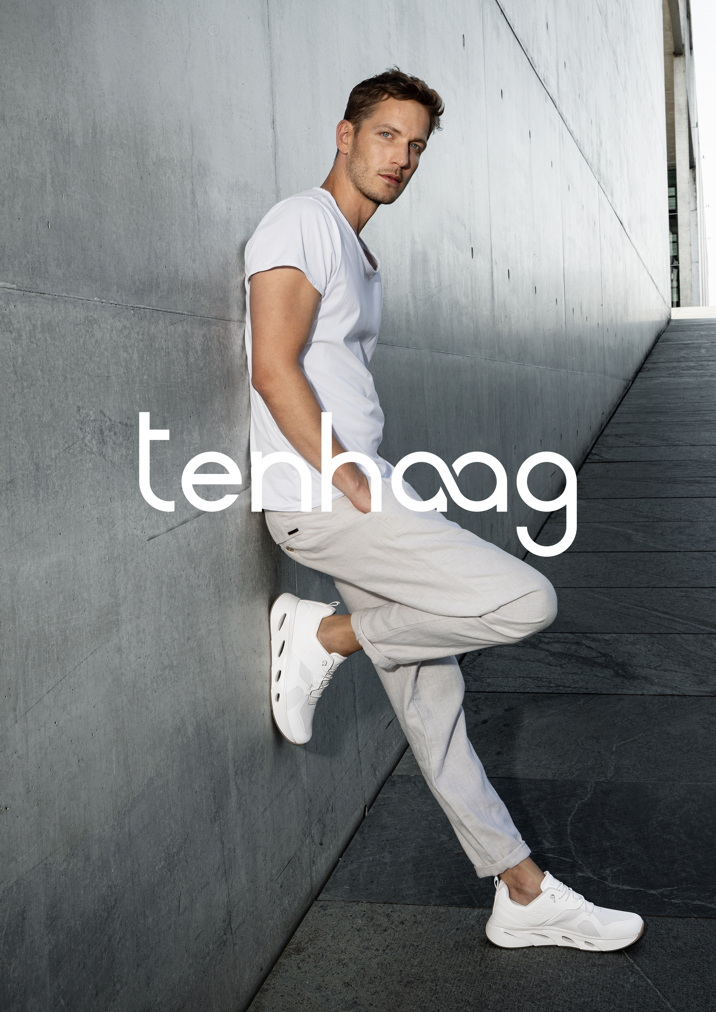 Mann lehnt an Wand unt trägt tenhaag sneaker