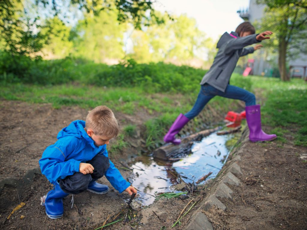 Kinder spielen in Gummistiefeln im Matsch