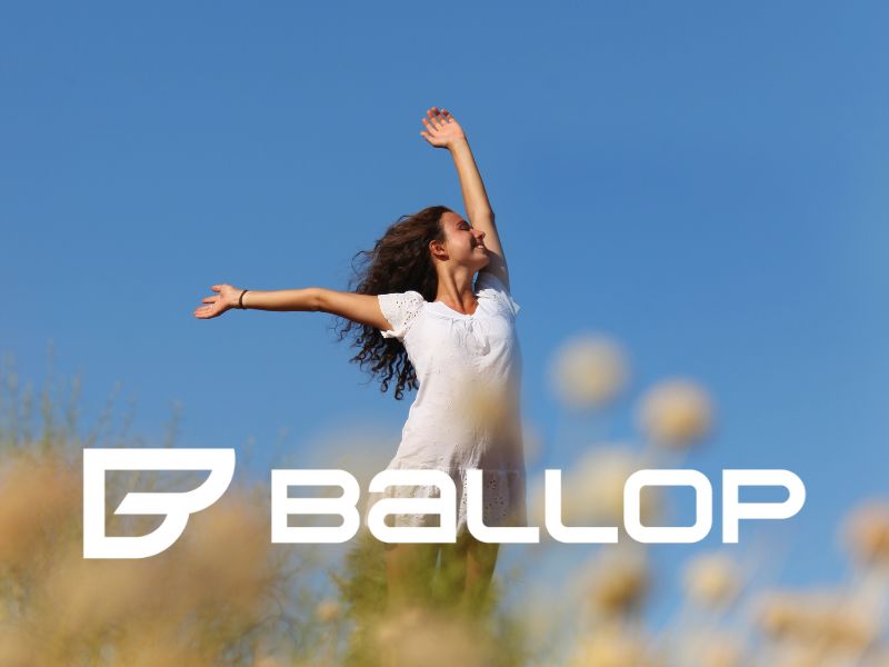 Frau reckt arme in den blauen himmel vor logo ballop