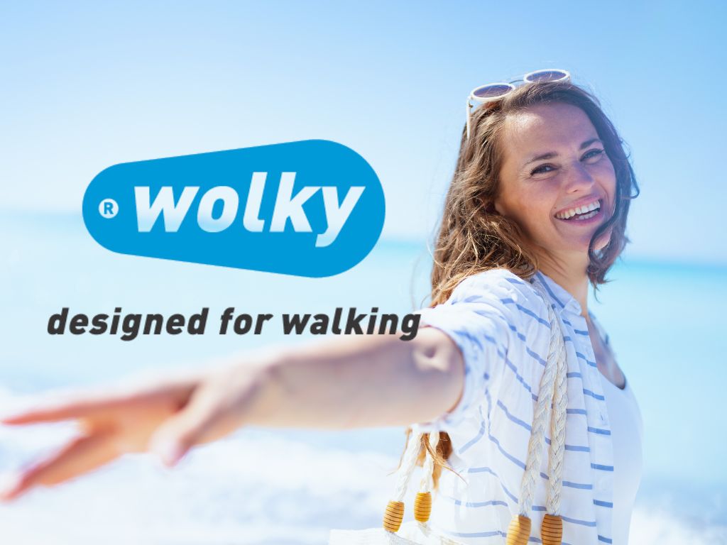 Frau am Strand mit logo der firma wolky und dem claim designed for walking