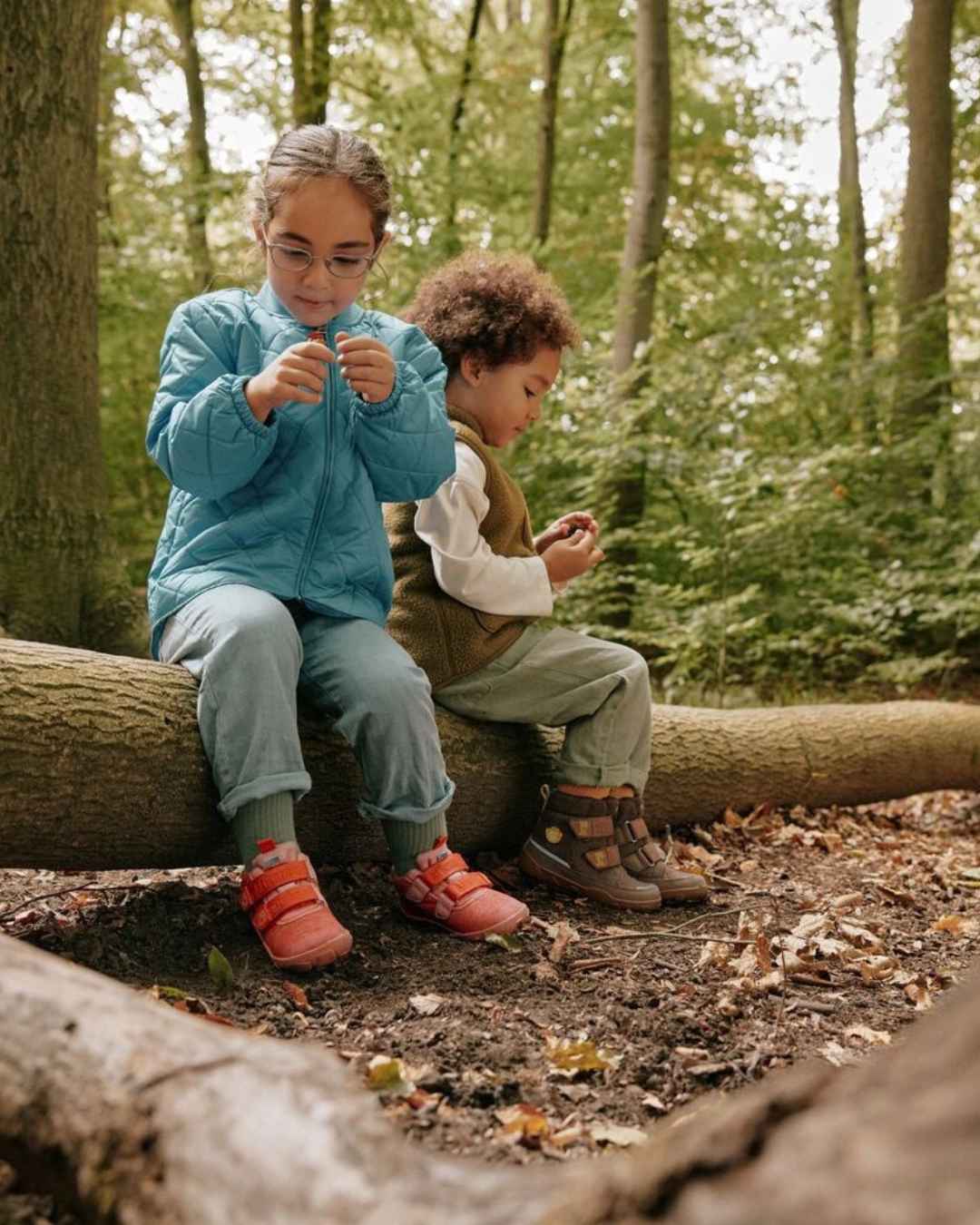 junge und mädchen siten auf umgefallenen baumstaumm im wald