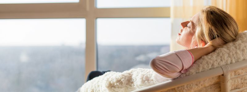 entspannt genießen Frau liegt im Sessel entspannt und genießt die Sonne im Fenster