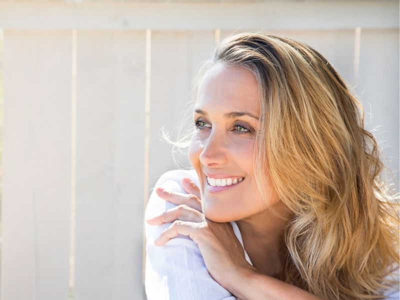 mittelalte frau stahlt vor siich hin