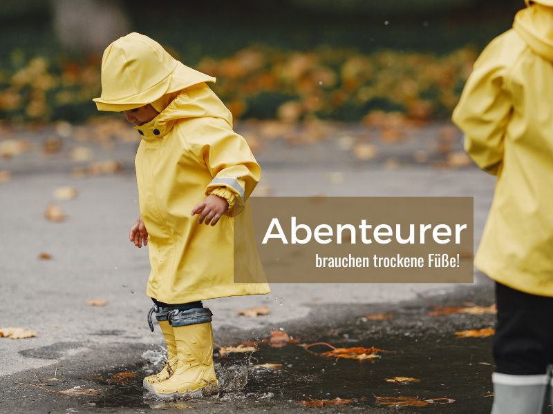 Kind in gelber Regenkleidung springt mit Gummistiefel in Pfütze