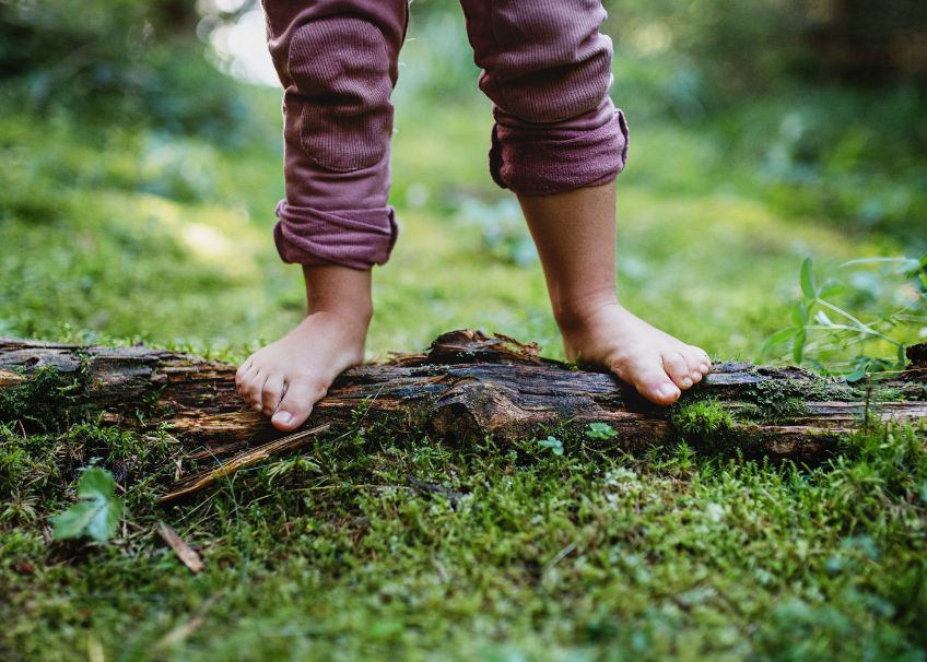 barfuß kids Kind steht barfuß auf Baumstamm